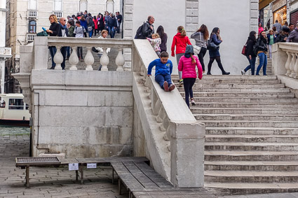 Boy sliding on railing of Rialto Bridge, Venice